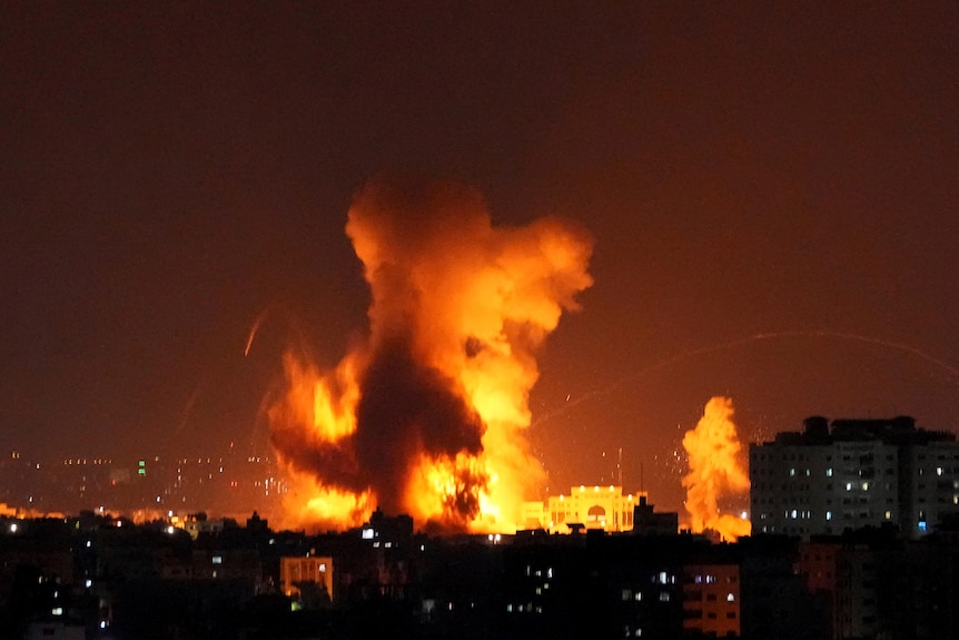 Smoke and flames rise in the distance following Israeli airstrikes on a building in Gaza City.