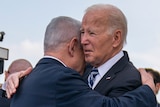 Joe Biden and Benjamin Netanyahu embrace as photographers film and take pictures.
