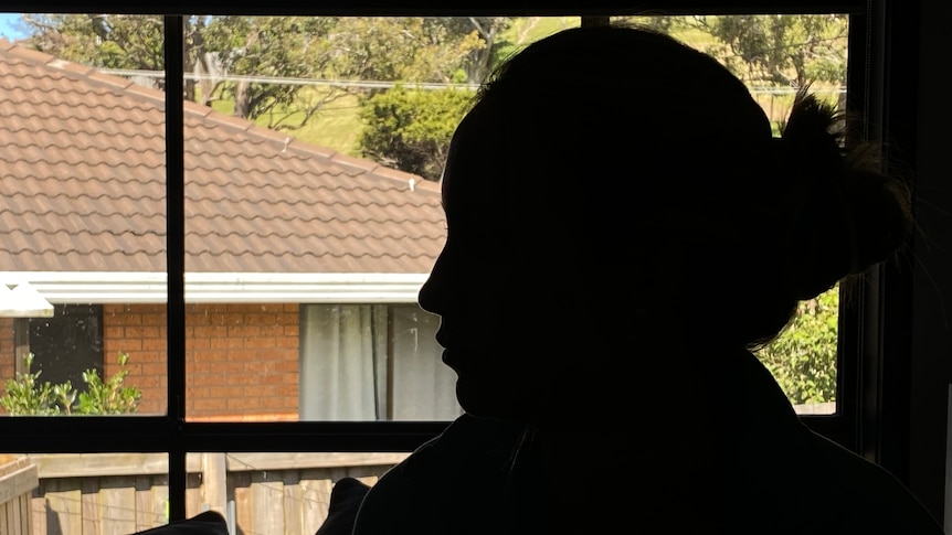 A silhouetted woman next to a window.