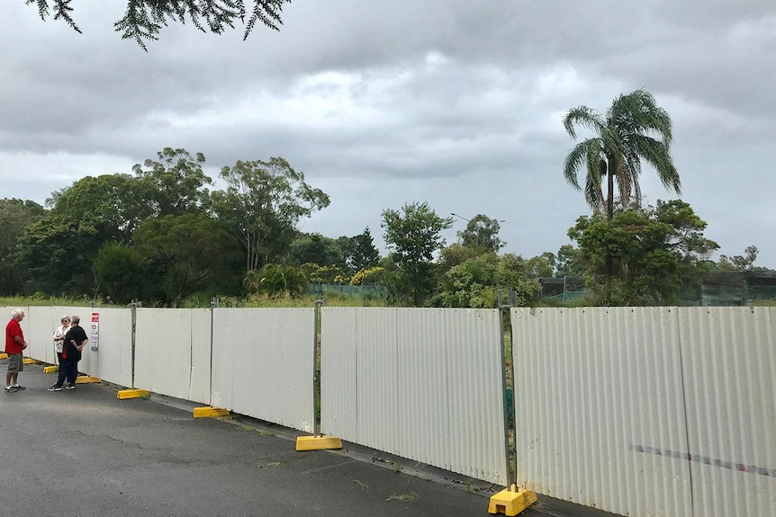 Julia and Anthony Mayfield stand with David Lambert next to temporary fencing outside their units