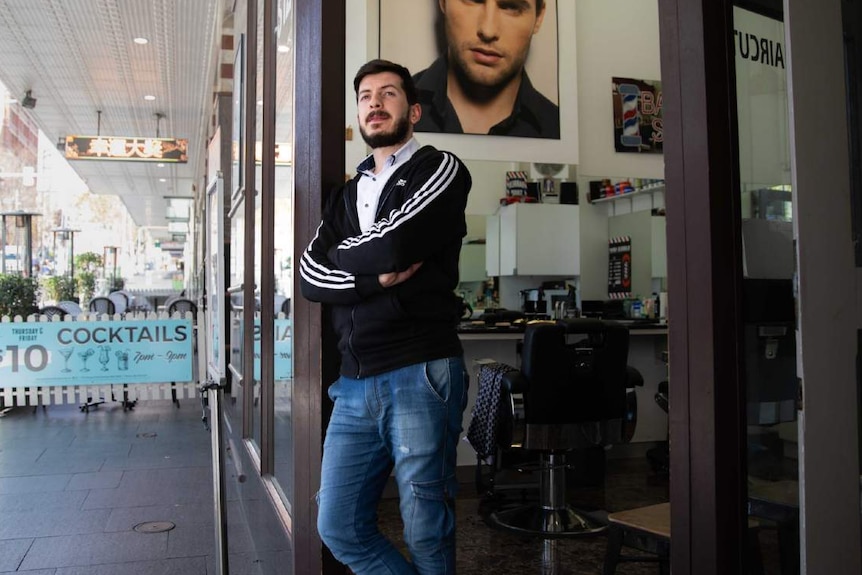 A man poses outside his barber shop