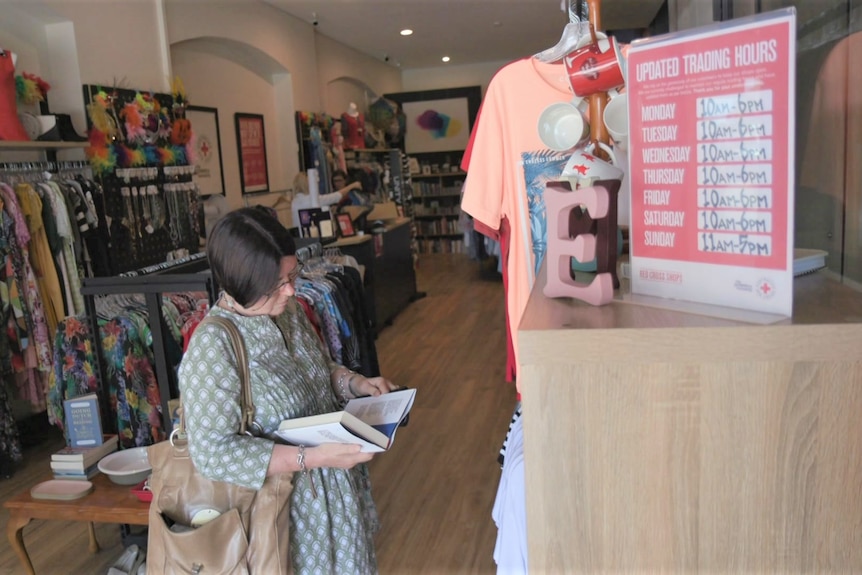 A women in a charity store flips through a book.