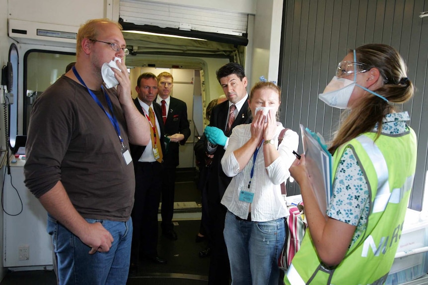 People with face masks at the entrance of a plane.