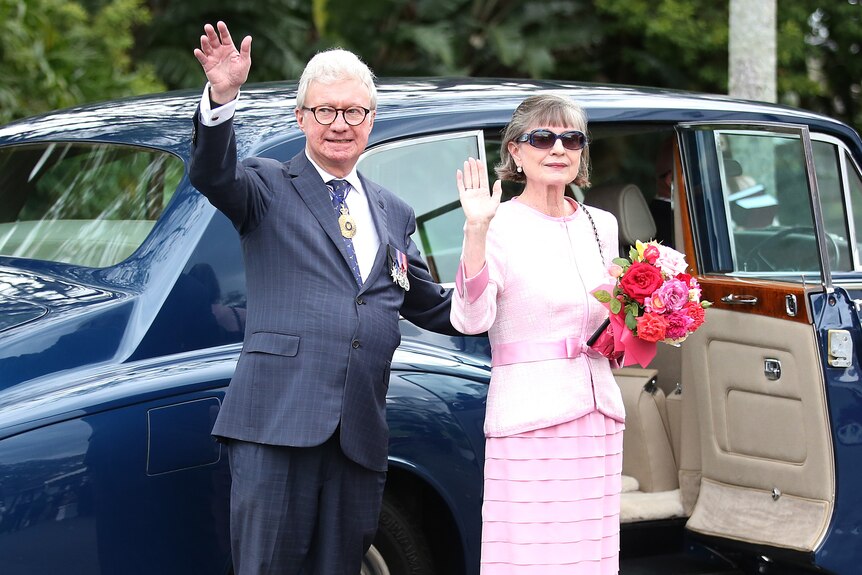 Paul de Jersey and his wife waving goodbye before stepping into a car.