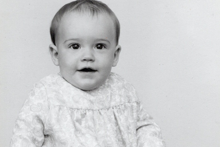 A smiling baby in an old black and white photograph. 