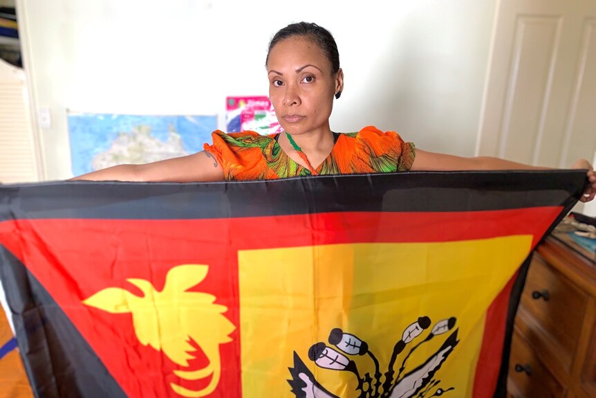 Woman holds out PNG flag in front of her.