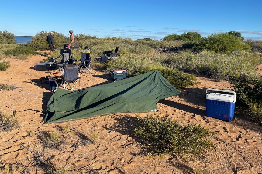 Basic camp in sand in a remote, rugged landscape.
