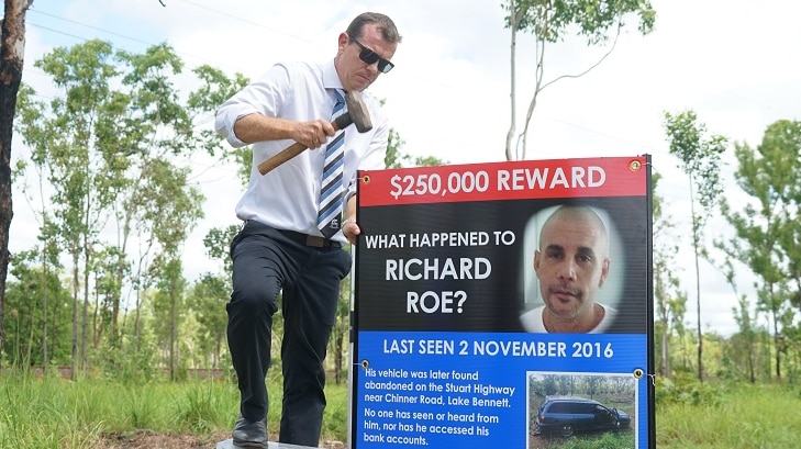 Senior Sergeant Matt Allen hammers in a sign about missing man Richard Roe