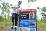 Senior Sergeant Matt Allen hammers in a sign about missing man Richard Roe