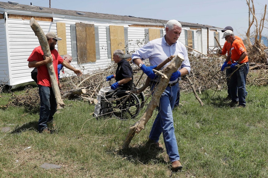 Mike Pence helps move tree debris during a visit to an area hit by Hurricane Harvey.