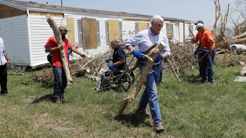 Mike Pence helps move tree debris during a visit to an area hit by Hurricane Harvey.
