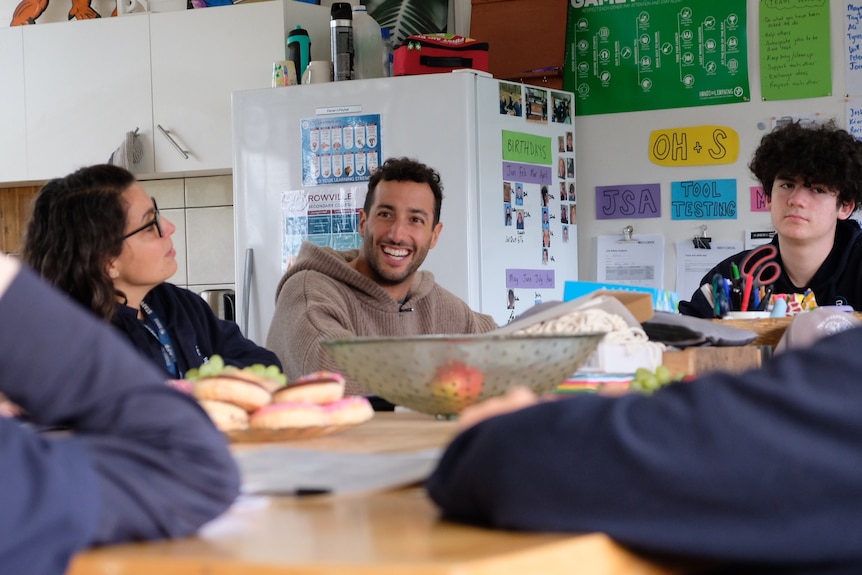 Daniel Ricciardo sits at table with students and laughs.