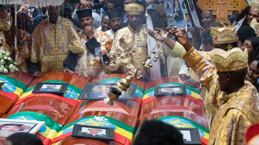 Empty coffins, with the pictures of airline crash victims placed on top, are carried through a public mourning ceremony