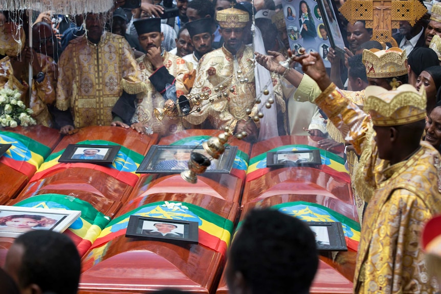 Empty coffins, with the pictures of airline crash victims placed on top, are carried through a public mourning ceremony
