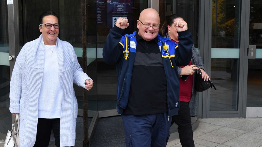 Wayne Greenhalgh smiles and raises his fists in celebration as he walks out of the court with his smiling wife by his side.