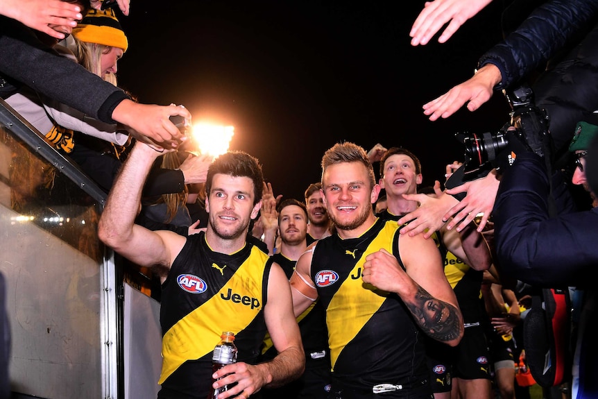 Trent Cotchin and Brandon Ellis shake hands with Tigers fans as they make their way down the race at the MCG.