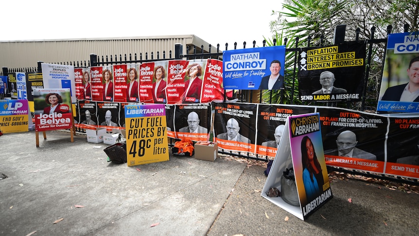 Labor and Liberal signs hanging on a fence. 