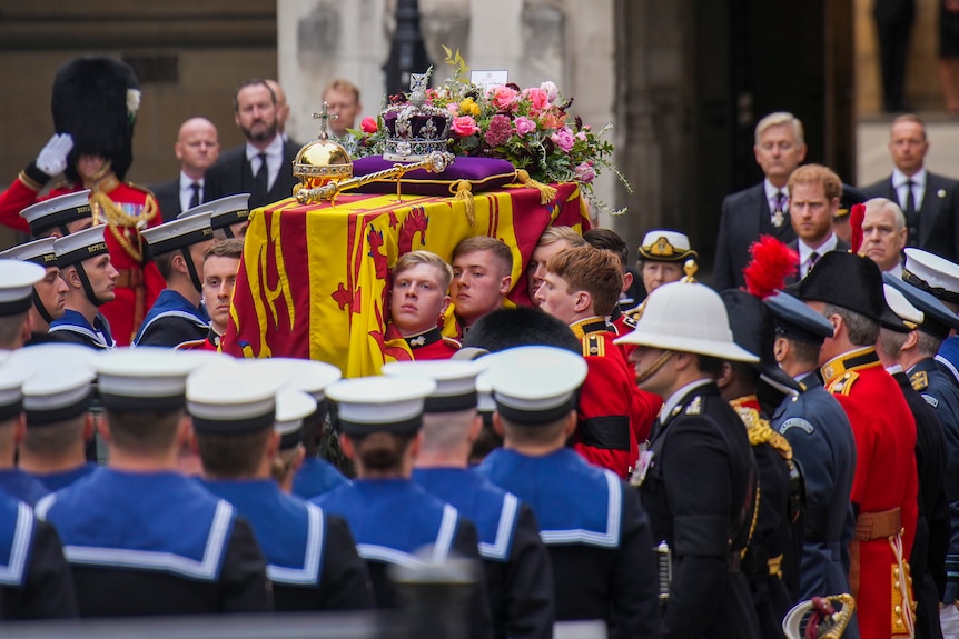 士兵们抬着裹着旗帜和鲜花的女王棺材 