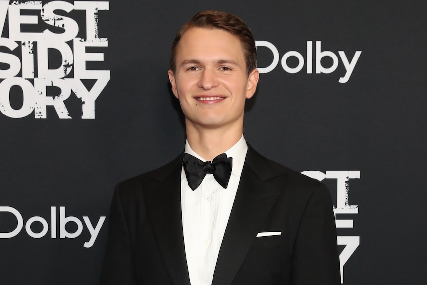 Ansel Elgort dressed in suit and bow tie, smiling at the camera