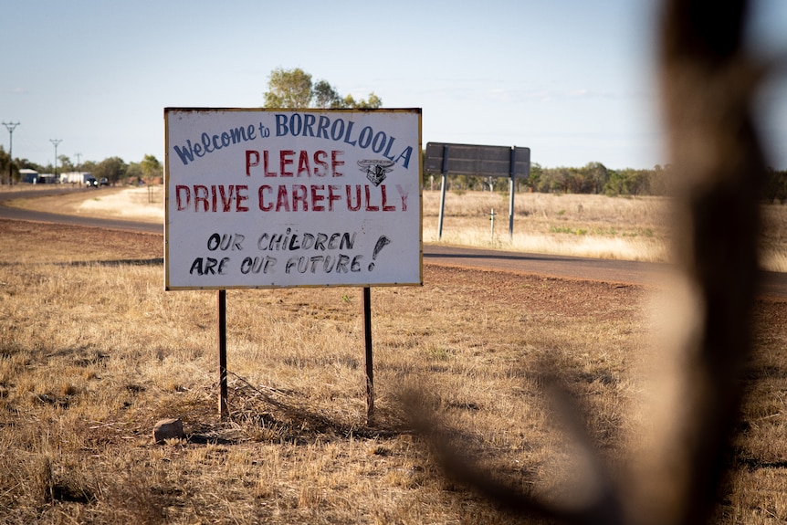 A welcome sign next to the side of the road in Borroloola, on a sunny day.