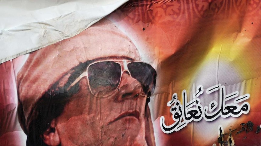 A poster of Libyan ruler Moamar Gaddafi burns during a demonstration in the north-central Libyan tow