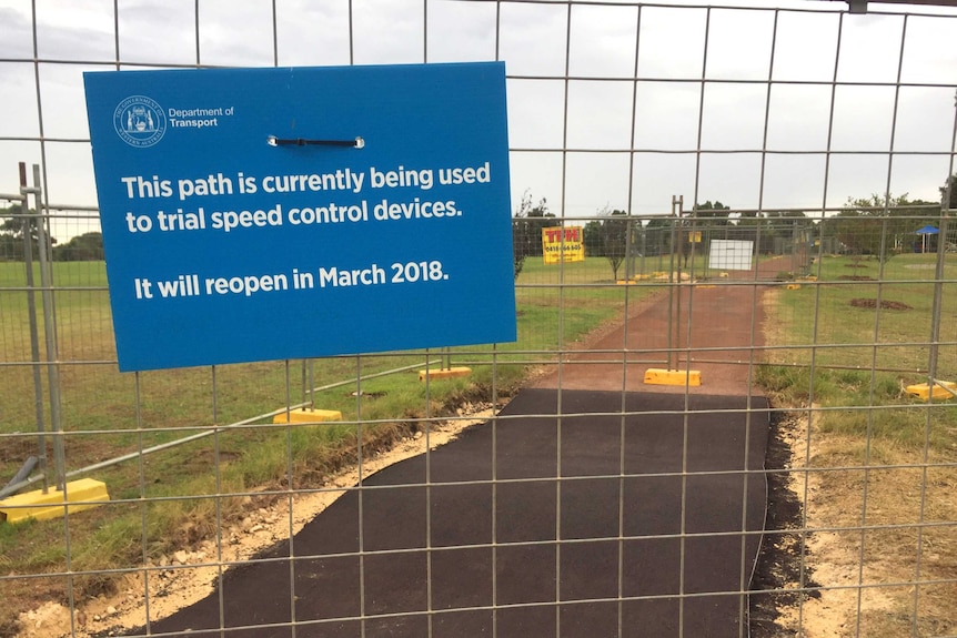 A fence with a sign saying: "This path is currently being used to trial speed control devices. It will reopen in March 2018".