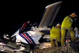 Emergency services officers look at the wreck of a light plane after it crashed near Cable Beach.