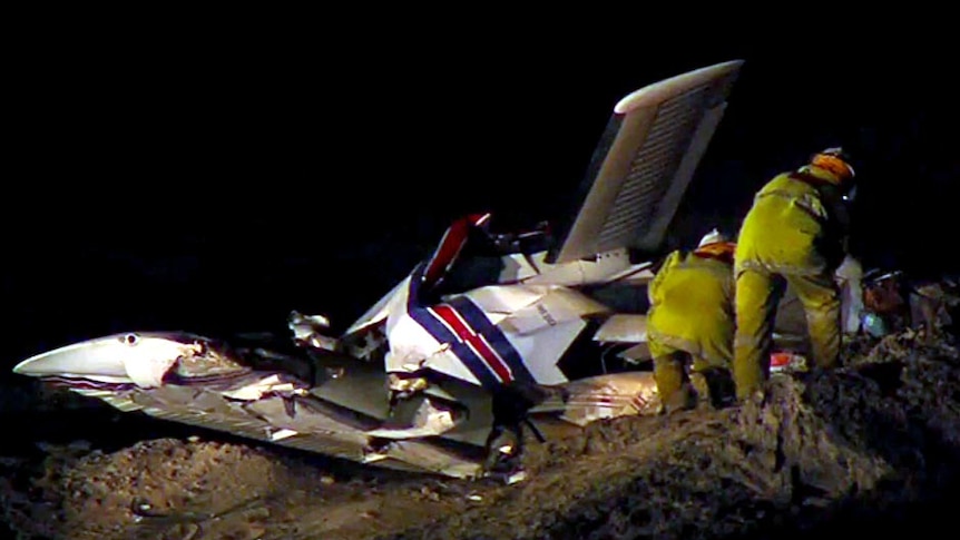 Emergency services officers look at the wreck of a light plane after it crashed near Cable Beach.