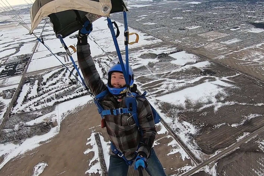 Un homme en parachute au-dessus d'un champ enneigé