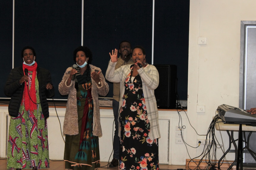 Women sing in a an indoor sports centre.