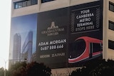 A large advertisement on the side of an apartment building, part of which reads "light rail stops here".
