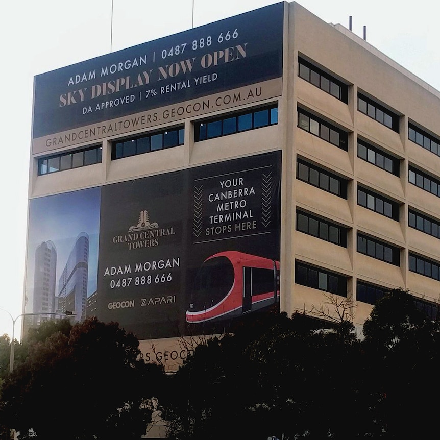 A large advertisement on the side of an apartment building, part of which reads "light rail stops here".