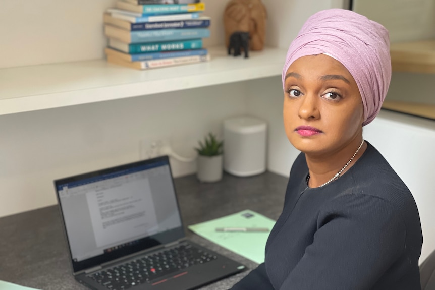 A woman sitting at a desk with a laptop in front of her