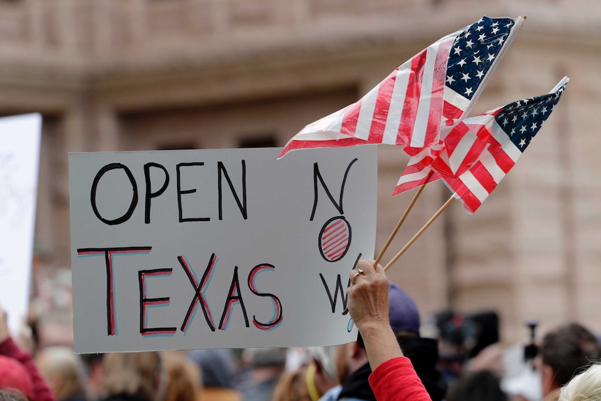 US flag and sign reading "open Texas now" at a protest in Austin, Texas.