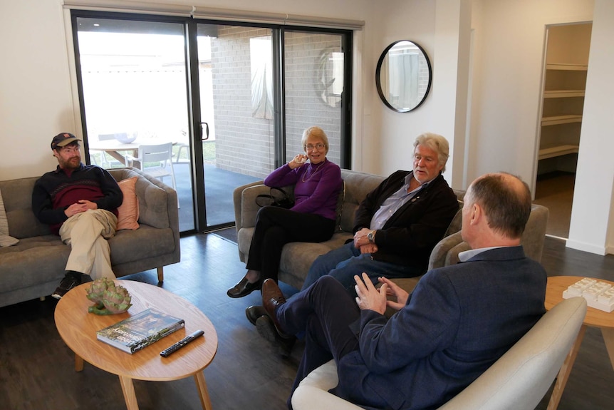 Four people sit talking in a light-filled living room