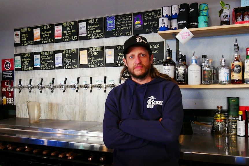 A man stands in front of a beer taps inside a brewery.