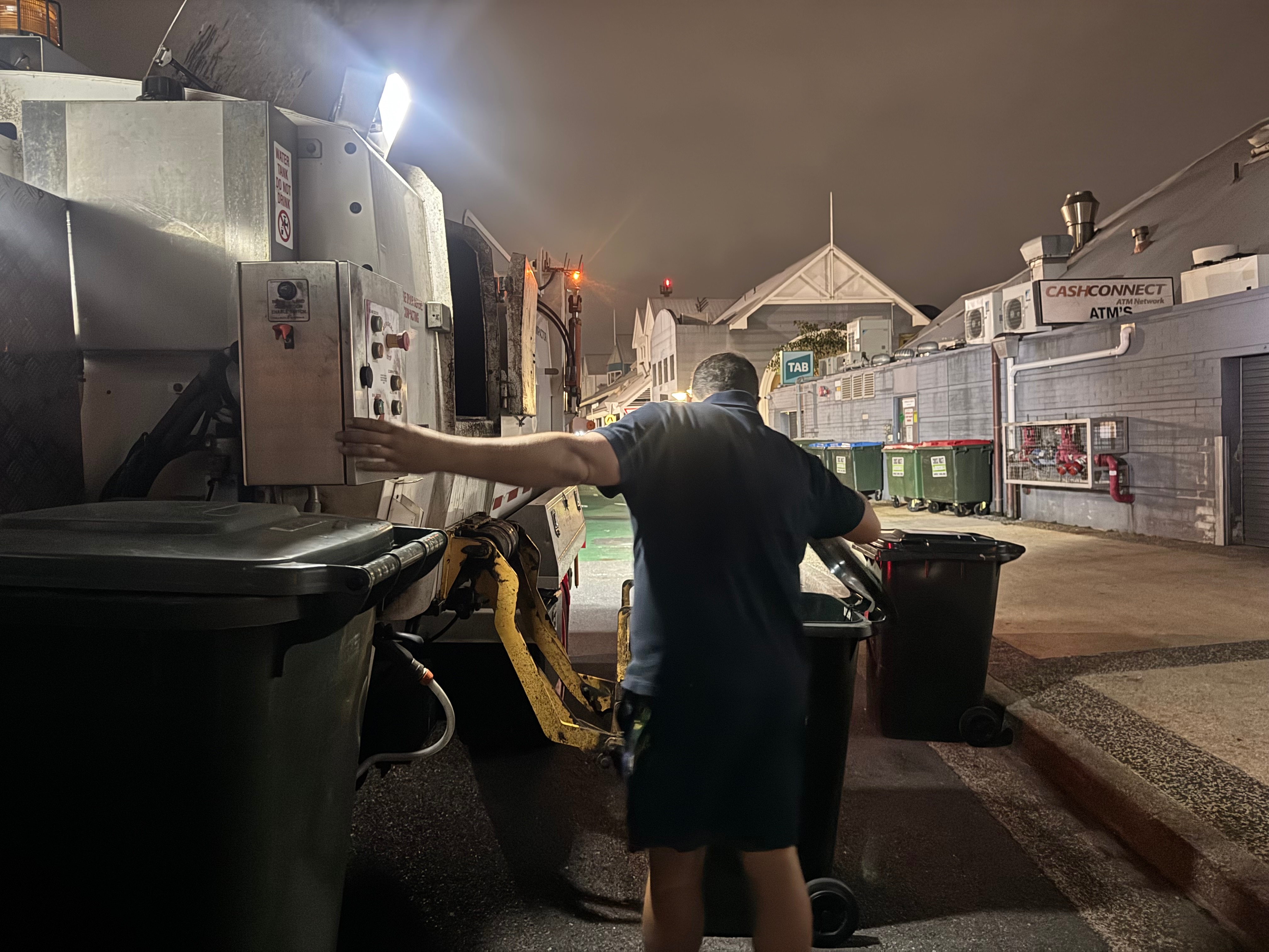 A man emptying restaurant bins at night 