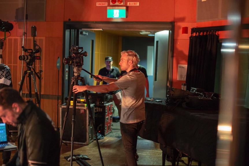 Cameras on tripods and Hallay behind one looking through a viewfinder.