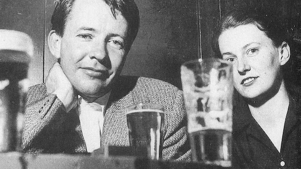 A 1950s black and white photo of a young man and young woman at a table with beers