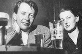 A 1950s black and white photo of a young man and young woman at a table with beers