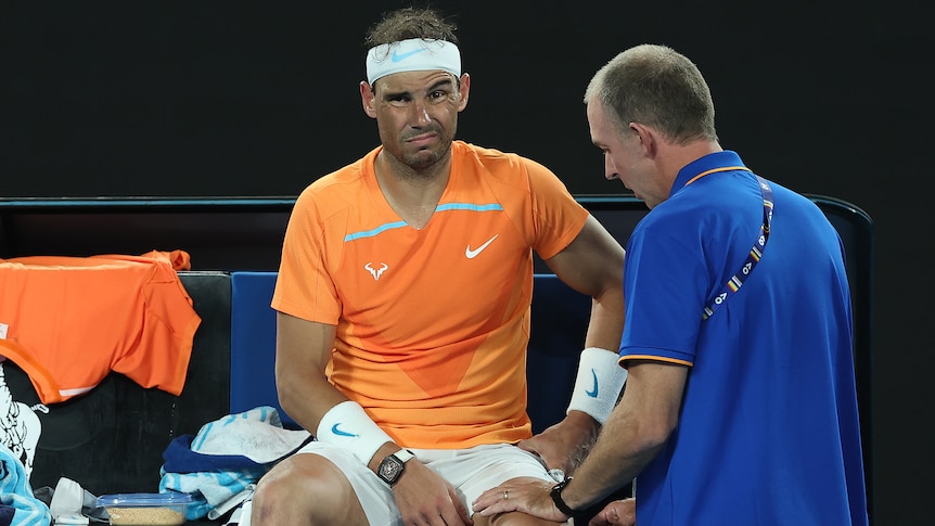 Rafael Nadal receives treatment from a trainer on court at the Australian Open.