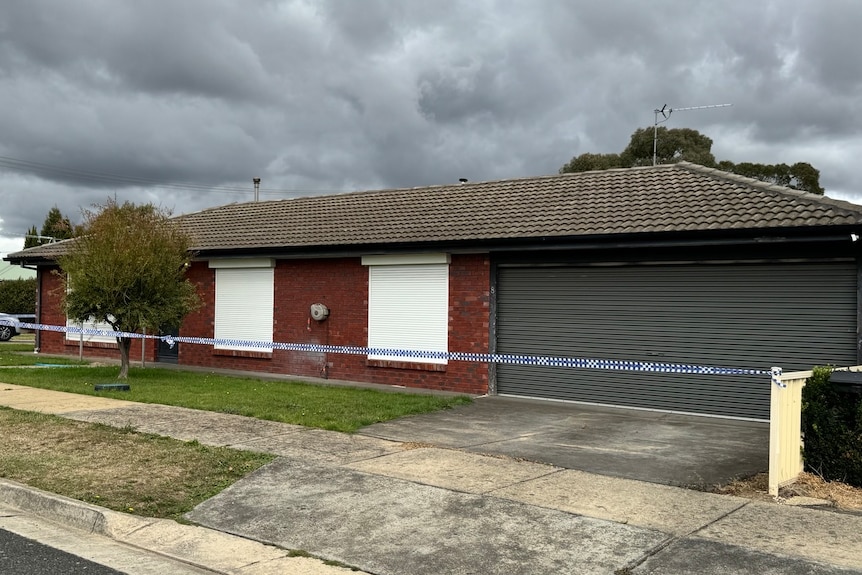 A brick house with crime scene tape in front of it.