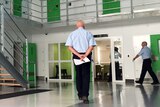 The inside of a prison with a guard standing with his back to camera