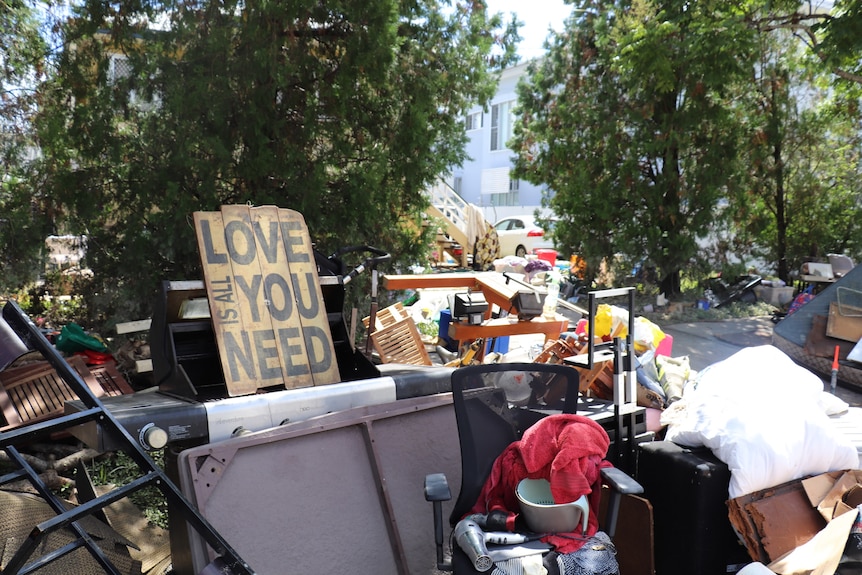 Flood-damaged household goods discarded at the front of a house