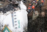 A rescue team works to recover the body of a victim from a plane crash in Nepal.