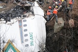 A rescue team works to recover the body of a victim from a plane crash in Nepal.