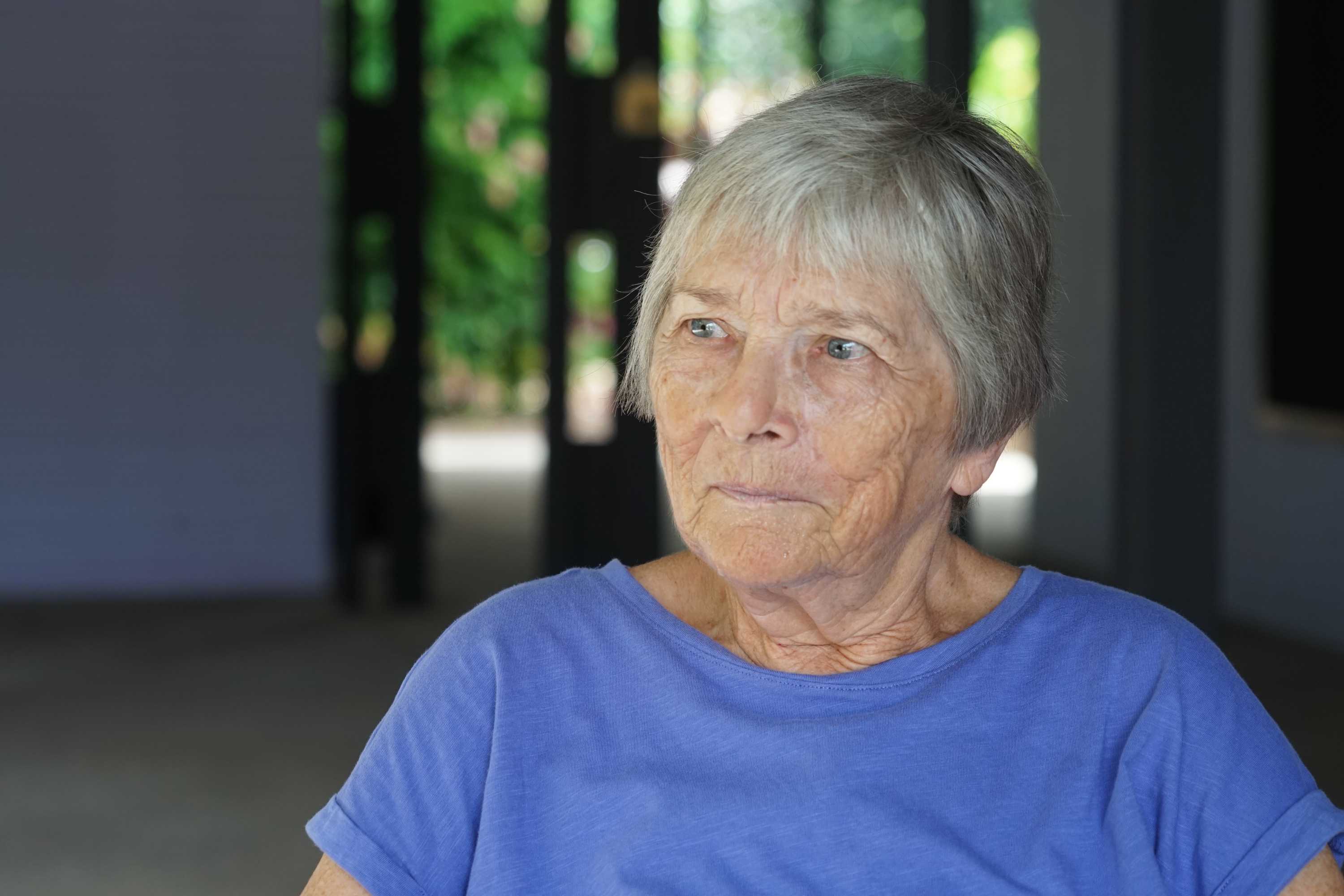 Jude Dent is looking seriously off camera. She has short grey hair and is wearing a blue shirt.