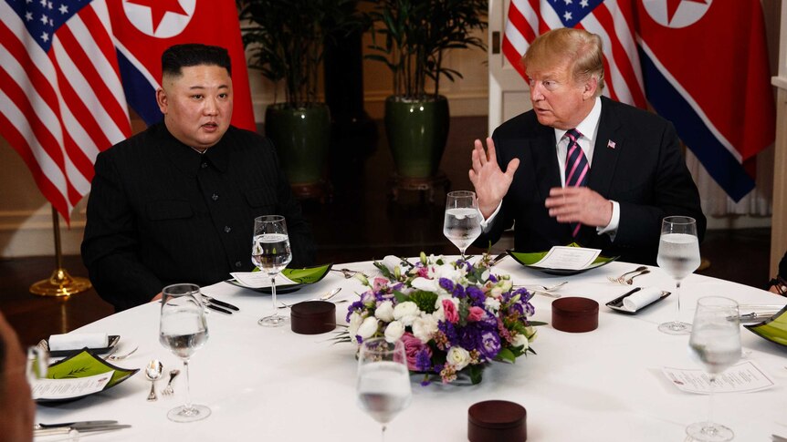 President Donald Trump sits at a table with North Korean leader Kim Jong Un.