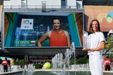 A tennis player poses with the Miami Open trophy - behind her a screen has her name, "2022 Women's champion".