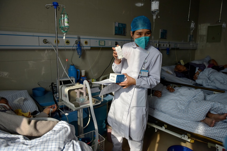 A nurse shows drugs to hospital patients on drips and ventilators.